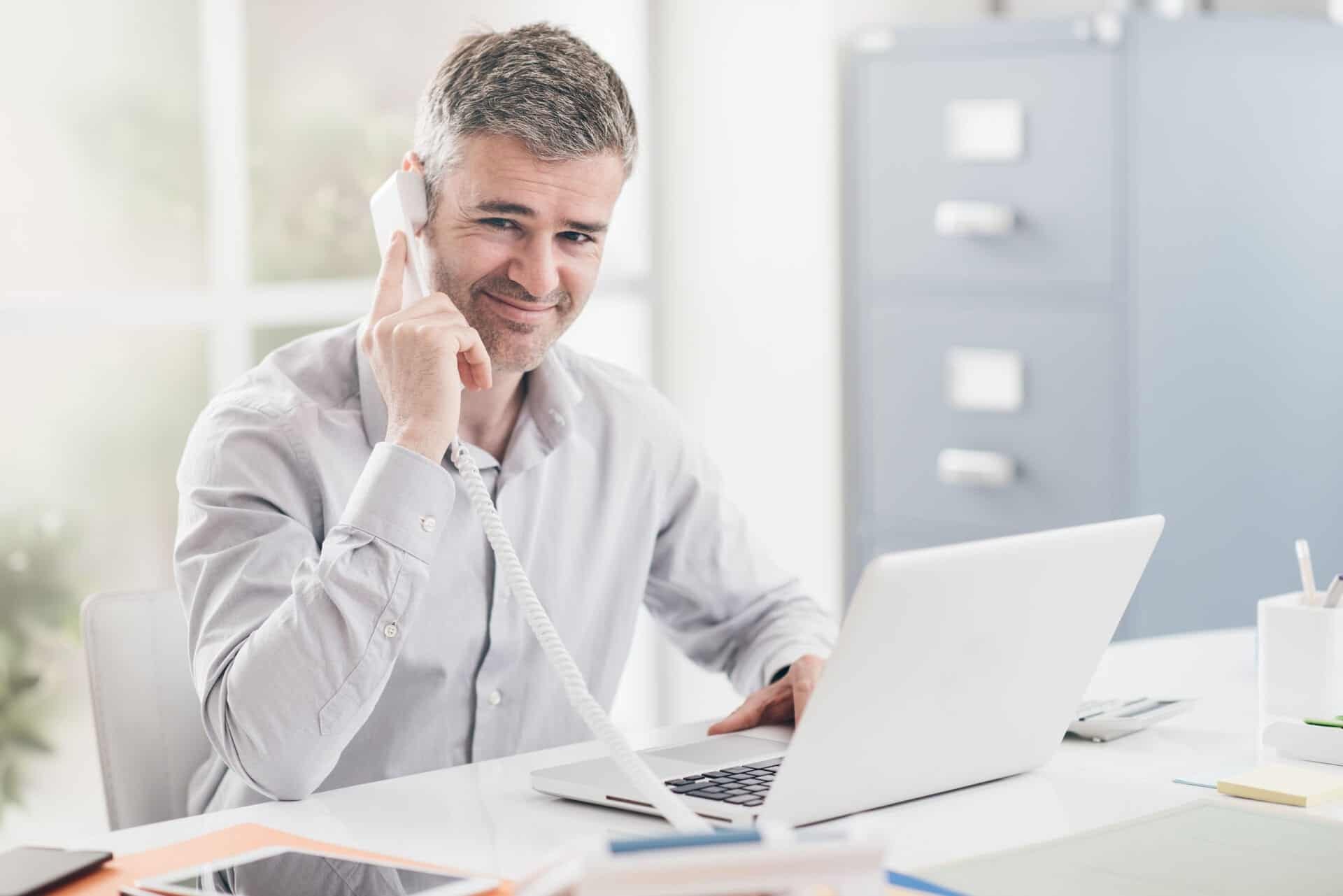 Confident smiling businessman and consultant working in his office, he is having a phone call: communication and business concept